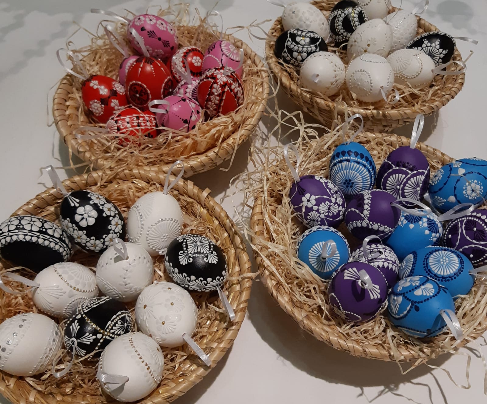 Mehrere Körbe mit kunstvoll handverzierten Ostereiern in verschiedenen Farben und Mustern – darunter schwarz-weiße, rote, violette und blaue Eier – präsentiert auf Stroh als Teil der Ausstellung „OsterEIER – Handwerkskunst“ im Zehnerhaus Bad Radkersburg.